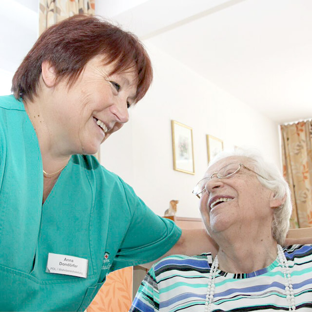 Eine Pflegekraft spricht mit einer älteren Dame