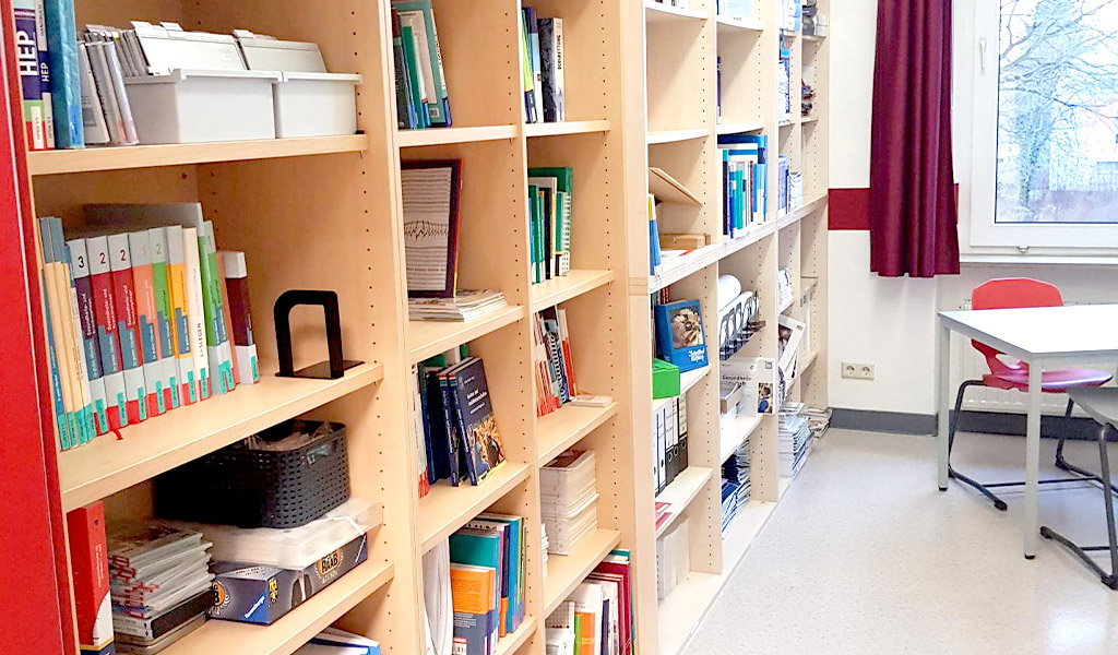 Schrank mit Büchern und Sitzmöglichkeit in der Bibliothek der BRK Schulen