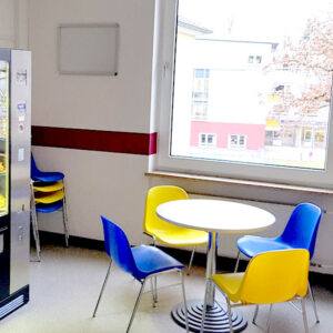 Tisch und Stühle im Pausenraum der Schüler mit Getränke- und Snackautomat
